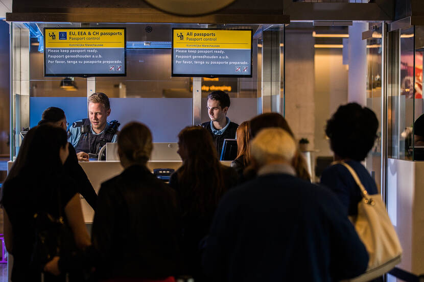 2 marechaussees bij de paspoortcontrole controleren reisdocumenten.