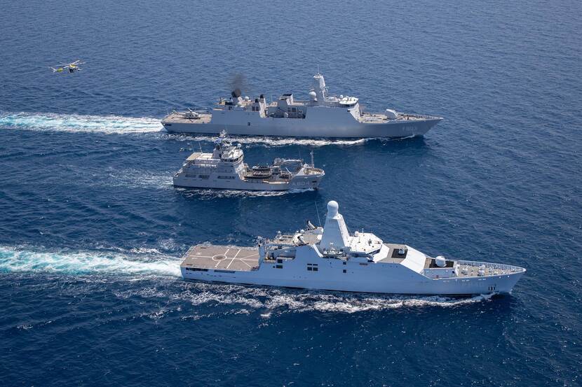 2 marineschepen op zee met in het midden een kustwachtvaartuig.
