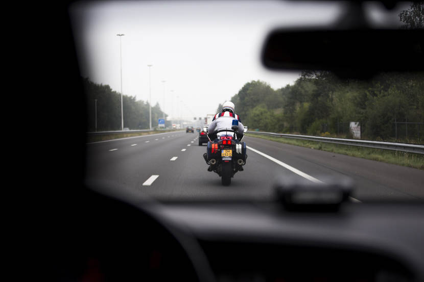 Motorrijder van de marechaussee begeleidt over de weg een waardetransport.