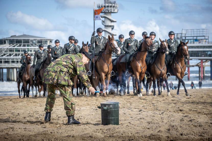 Een militair steekt een rookbom tijdens het oefenen met paarden voor Prinsjesdag.