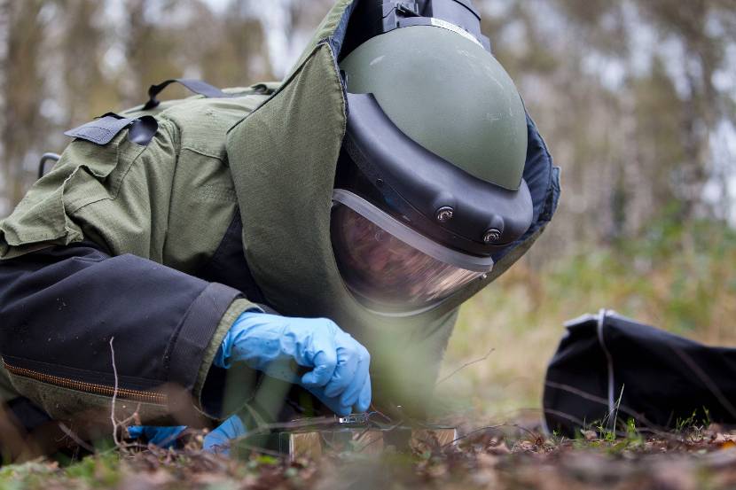 Een explosievenruimer in een bommenpak ontmantelt een oefenexplosief.