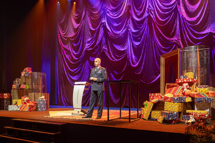 Een militair op het podium spreekt voor de aanwezigen.