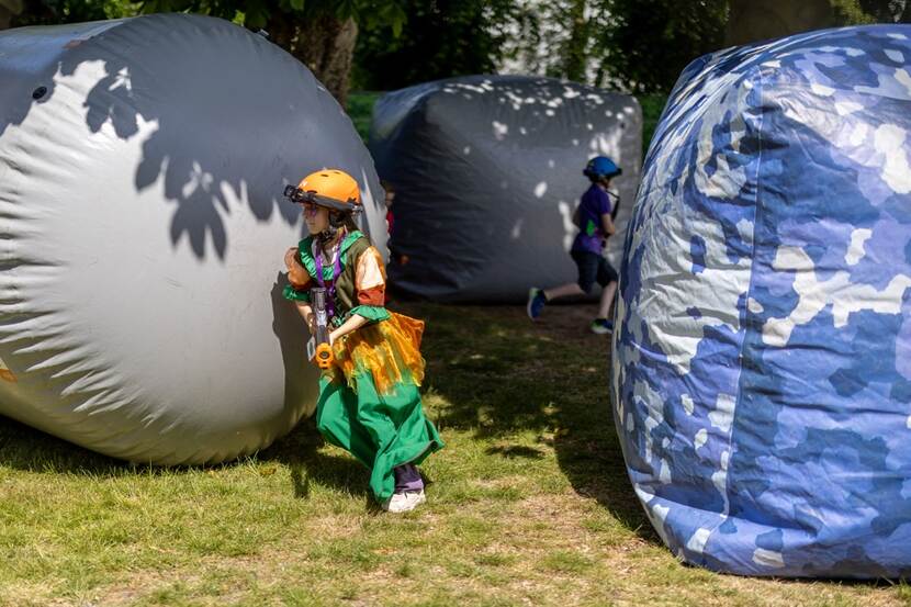 Een kind verstopt zich tussen hele grote opblaasballen.