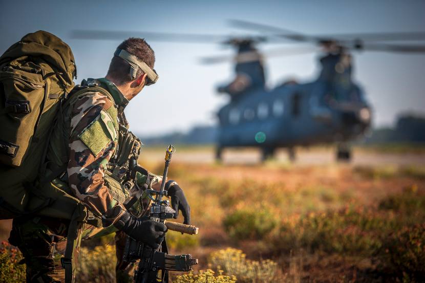 Luchtmobiele militair wacht voordat hij aan boord kan van de Chinook-transporthelikopter op de achtergrond, oefening Hot Blade 2014.