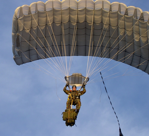 Een parachutist met een rugzak die aan hem is vastgeketend.