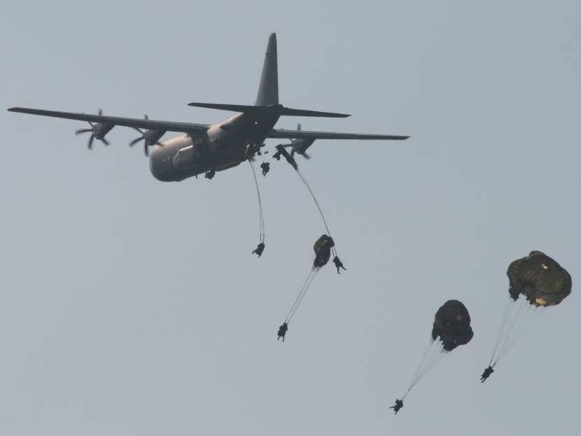 Parachutisten springen volgens de static line methode uit een vliegtuig.