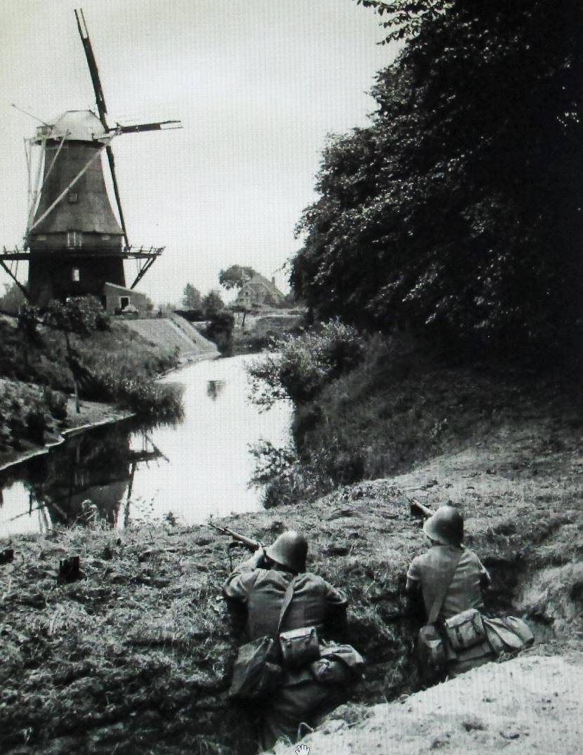 Militairen Vrijwillige Landstorm in dekking bij molen.