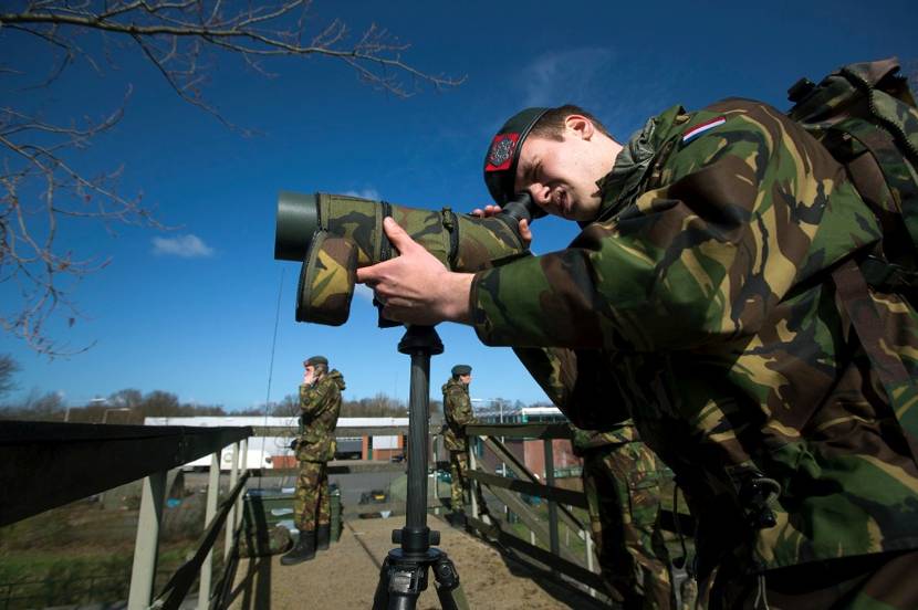 Militairen Korps Nationale Reserve met kijker en radiocontact.