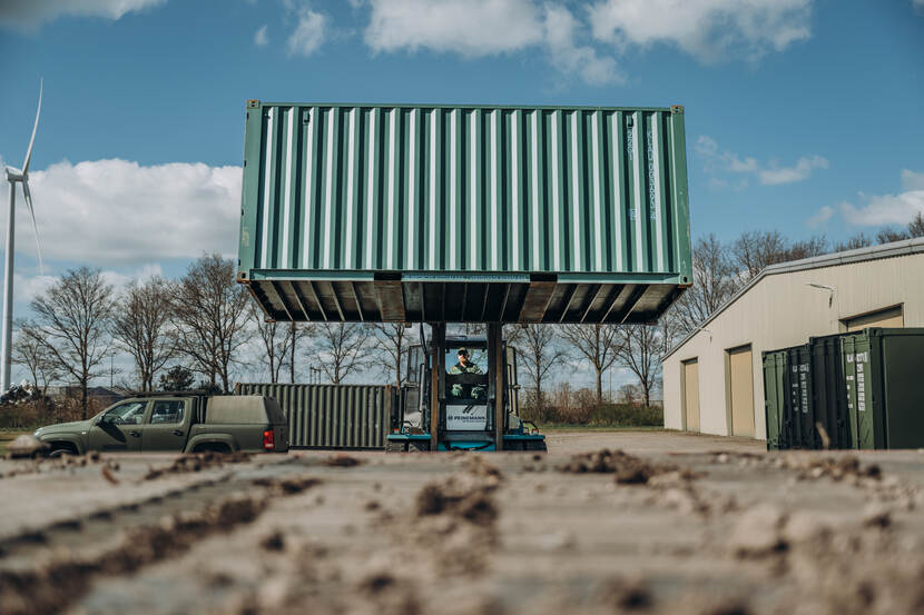 Een heftruck tilt een container op.