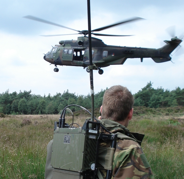 Een militair communiceert vanaf de grond met een helikopter.