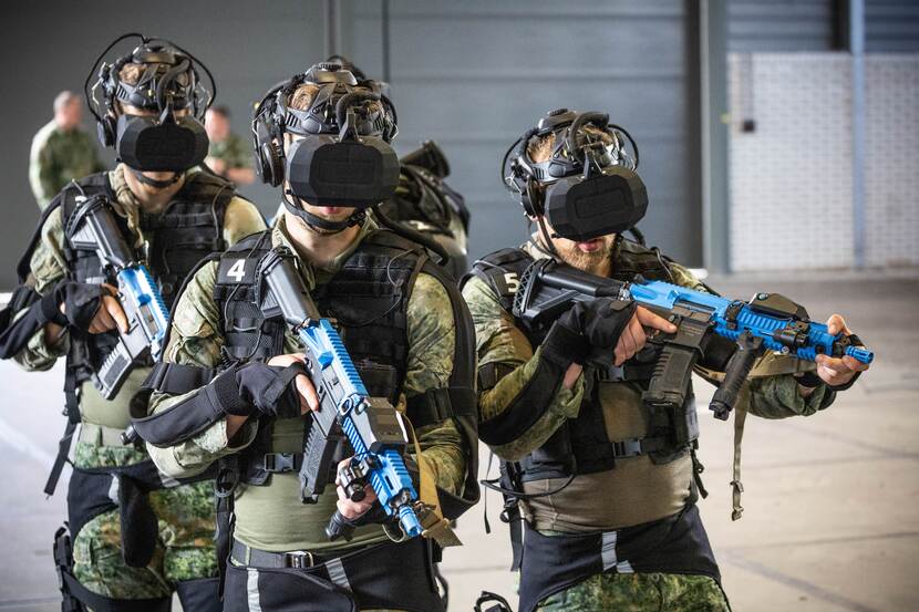 3 landmachtmilitairen  in camouflagepak met VR-bril en wapen.