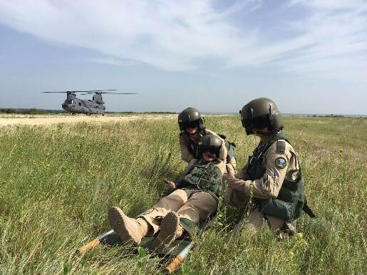 2 militairen helpen een gewonde collega tijdens een oefening.