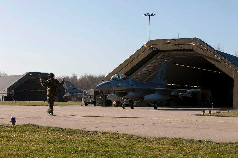 Een F-16 komt uit een hangar.