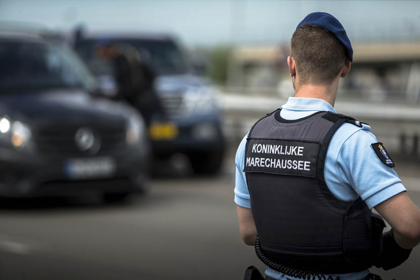 Een marechaussee staat paraat bij een luchthaven.